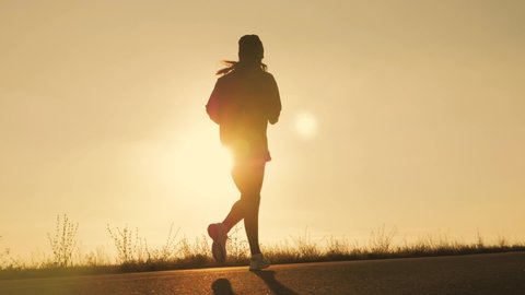 Silhouette fitness sport women running on road at sunset. Athlete runner feet running on road.