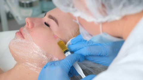 PRP therapy in beauty clinic. Cosmetologist is doing injections of blood plasma to womans face to cure problem skin, closeup side view. Treatment of skin in cosmetology for young female.