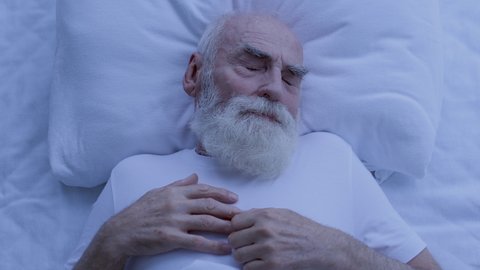 Greyhaired man waking up in bed, sleeping disorder, disturbing dreams at night