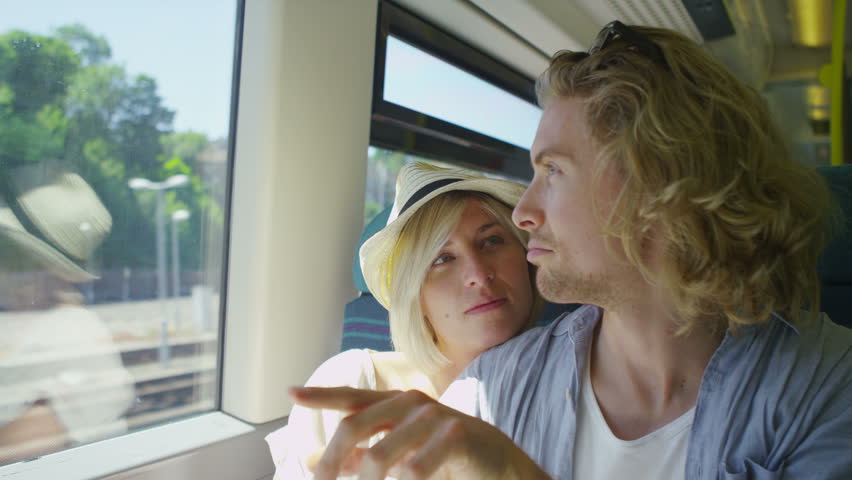 4K Attractive man talks to his girlfriend about whats outside the train window on a journey as she listens in slow motion, shot on RED EPIC | Shutterstock HD Video #10647374