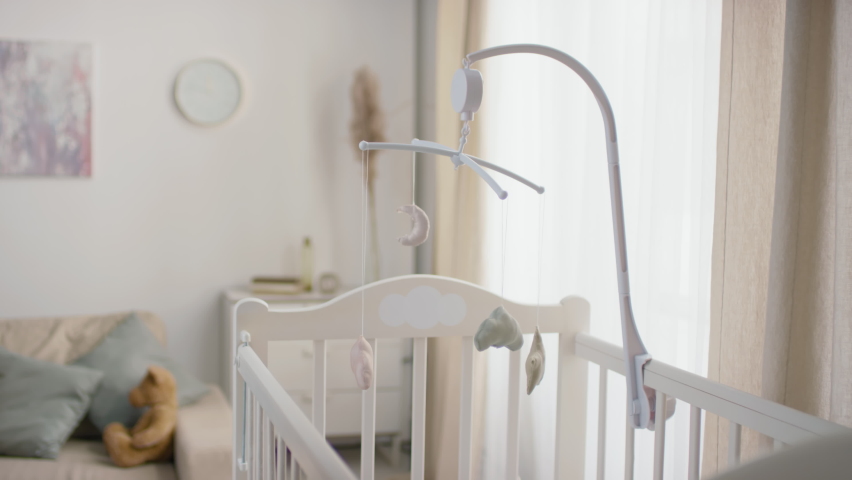No people slowmo footage of beautiful homemade crib toys hanging above white baby cot standing in pastel-colored living room Royalty-Free Stock Footage #1064746882