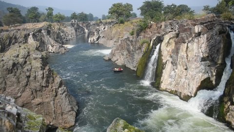 beautiful view clip video of hogenakkal waterfalls flow from rocks with blue sky green background