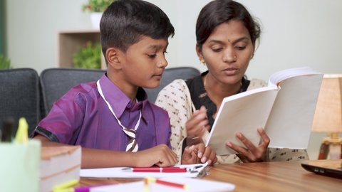 Indian Mother helping son to do school homework - concept of parental support for education during childhood