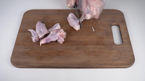 Chicken wings cutting. Human hands cut raw chicken wings into pieces.