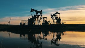 Oil pumping units operating at sunset, reflected on water surface - Powered by Shutterstock - Get 15% off with code: PIKWIZARD15