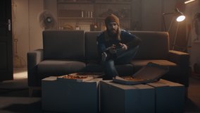 POV Portrait of young Caucasian man playing video game inside home garage, enjoying pizza. Shot with 2x anamorphic lens