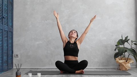 Fitness, sport and healthy lifestyle concept - woman working out at home or in yoga studio. Relaxed young female doing stretching exercise on yoga mat. Attractive girl meditating.