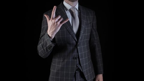Handsome businessman wearing suit showing rock n roll sign with his hand isolated on black background. Caucasian man wearing plaid blazer business suit gesturing showing heavy metal sign