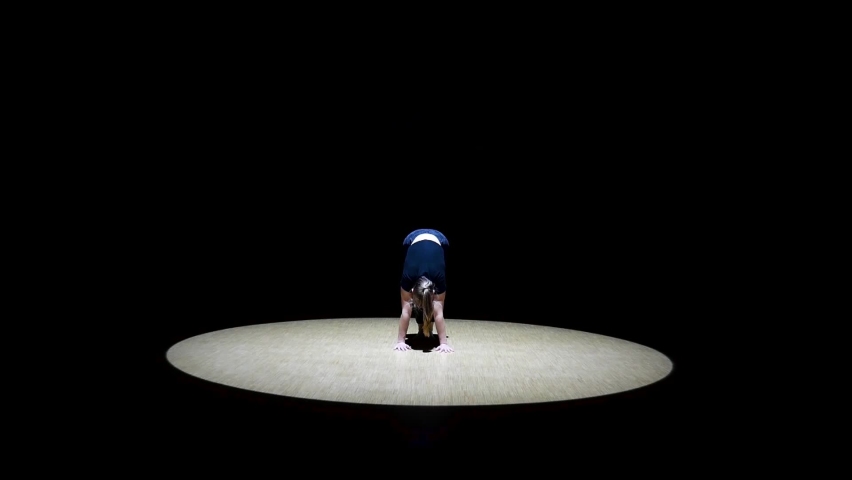 Female Performer does handstand in different positions on stage in a epic spotlight Royalty-Free Stock Footage #1064793589