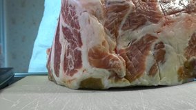 A woman cuts a large piece of pork meat with a knife. Meat with fat layers, pork neck.