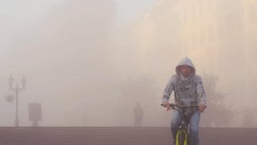 A man carries a bicycle through the mist of a modern city, through the stairs. Autumn, thick fog. Then he gets on his bike and leaves. - Powered by Shutterstock - Get 15% off with code: PIKWIZARD15