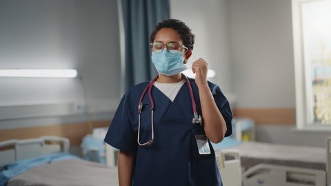 Hospital Ward: Portrait of Posing Professional Black Female Nurse, Doctor, Surgeon Wearing Face Mask Looks at Camera, takes off the Mask and Reveals Beautiful Smiling Healthy Self. Modern Clinic