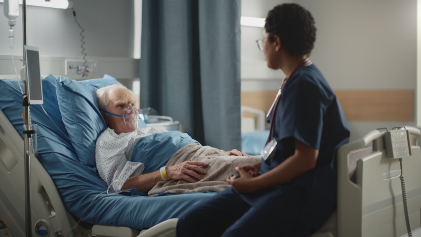 Hospital Ward: Friendly Head Nurse Connects Finger Heart Rate Monitor or Pulse Oximeter to Elderly Patient Wearing Oxygen Mask Resting in Bed. Nurse Does Patient Checkup After Successful Surgery Royalty-Free Stock Footage #1064816731