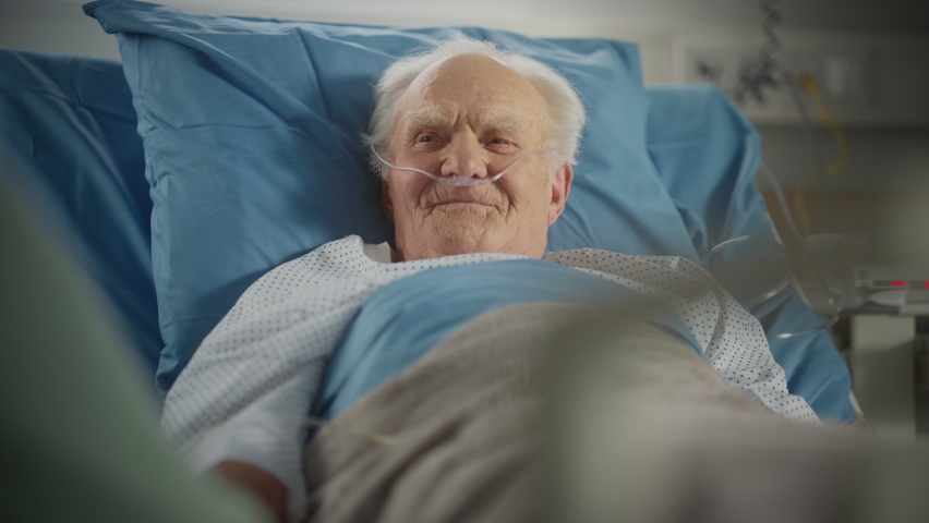 Hospital Ward: Portrait of Handsome Elderly Man Resting in Bed, Fully Recovering after Sickness and Successful Surgery. Old Man Smiling, Remembering His Happy Long Life, His Family and Friends Royalty-Free Stock Footage #1064816755