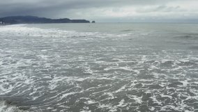 Still video showing the small waves of the Pacific Ocean running into the beach