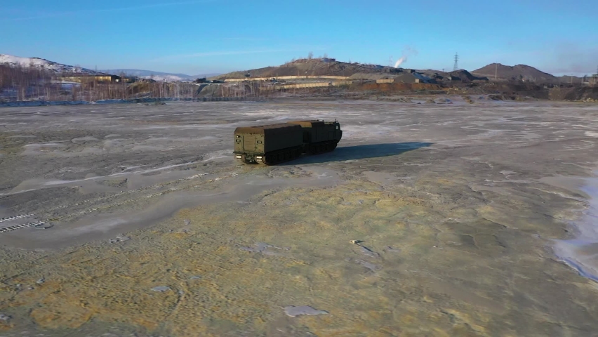 Military tracked all-terrain vehicle in motion at the quarry, general plan aerial photography