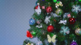 On a light gray background, a green Christmas tree decorated with colorful butterflies and toys