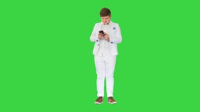 Young teenager boy in business suit using mobile phone on a Green Screen, Chroma Key.