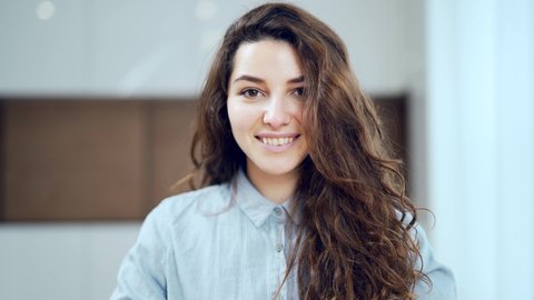 Portrait of a Gorgeous Dark Haired Hispanic Woman Smiling Charmingly while. Charming Curly Young Girl in a Room Indoors Smiling and Looking at the Camera. Close up Face Attractive Confident Student