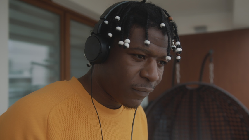 Happy african american black man listening to the music and pretending to play guitar on the balcony. High quality 4k footage