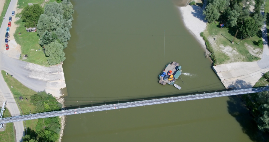 The aerial view of the footbridge and a ferry on the river (Kriznica on the Drava River in Croatia)