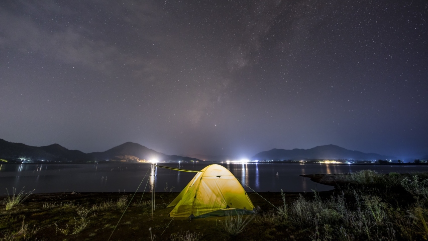 milky way and stars of night clear sky above mountain with camping tent 