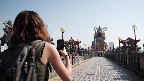 Girl taking photo with her mobile of Pagoda at Lotus Pond in Kaohsiung, Taiwan. Mid angle, parallax movement, slow motion, HD.