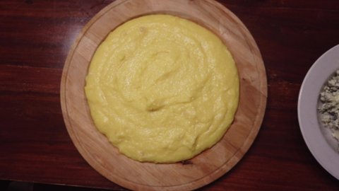 4k short video of a plate of very hot traditional creamy polenta, a plate of gorgonzola cheese and a plate of walnuts