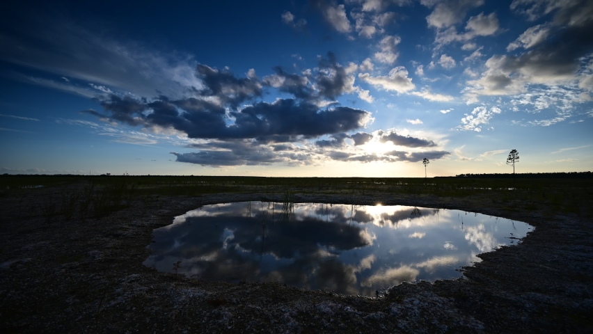 Timelapse of sunset over Hole-in-the-Donut habitat restoration area in Everglades National Park, Florida reflected in water of exposed solution hole 4K.