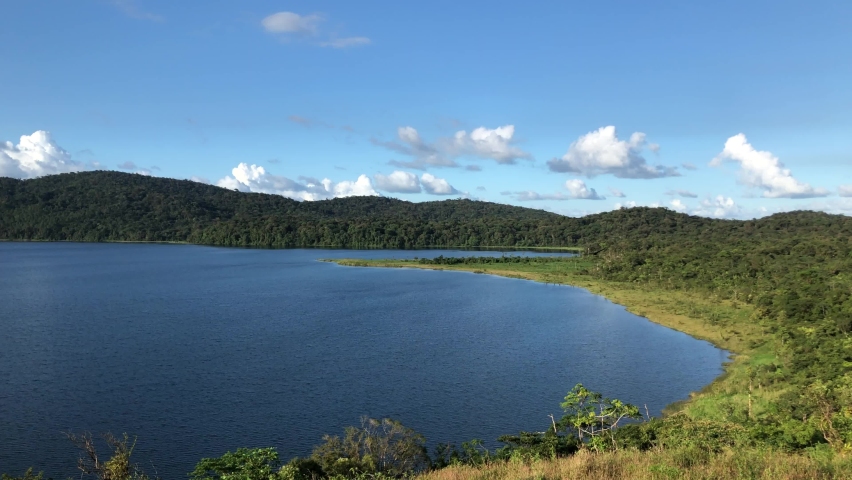 Ancient blue water lake view on clear day: 4K video of prehistoric Lake Cote, Costa Rica, with raptors discretely flying across the frame.