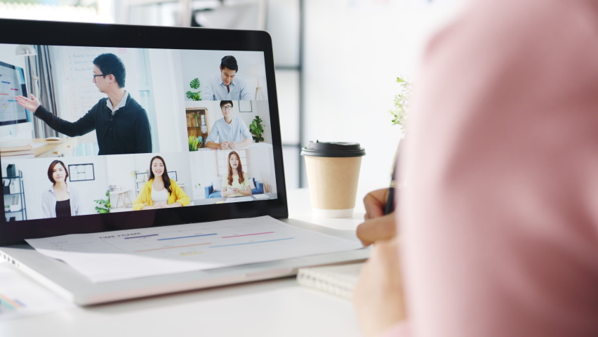 Young Asia businesswoman using laptop talk to colleague about plan in video call meeting while work from home at living room. Self-isolation, social distancing, quarantine for corona virus prevention. | Shutterstock HD Video #1064856769