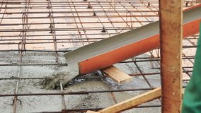 Pouring concrete mixture to the reinforcing mesh and a house foundation. Clip. Pouring liquid cement at a construction site. 