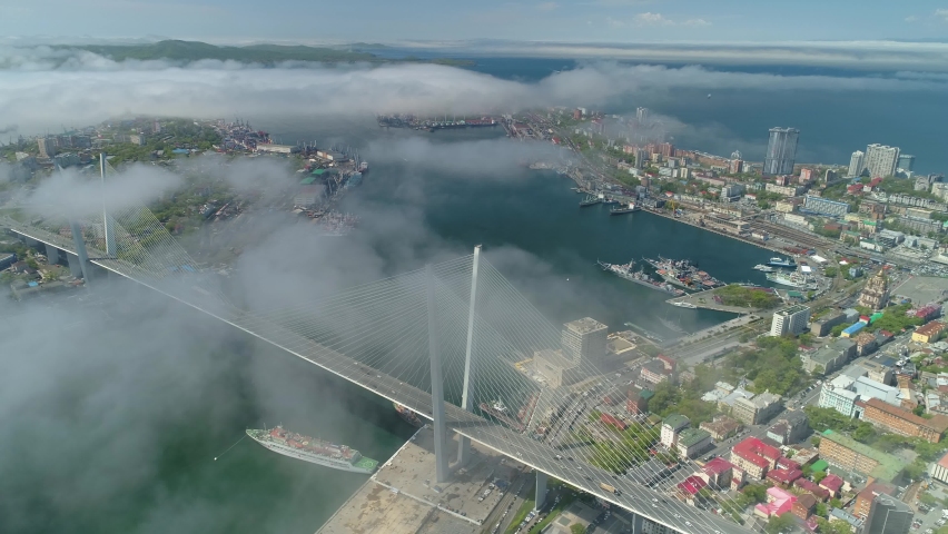From great height unique view center cityscape Vladivostok Far East, peninsula, modern Golden bridge. Cumulus clouds low white fog. Epic best downtown. Cinematic stock film. Best travel video. Aerial Royalty-Free Stock Footage #1064858170