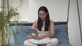 Cute funny indian girl talking to friend, sister, mom or distance  during online virtual family chat videocall meeting by video conference call using tablet sitting at home desk.