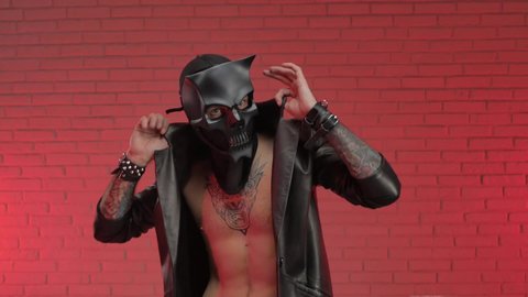 a man wearing a demon skull mask in a leather cloak with leather bracelets and straps on his body dances