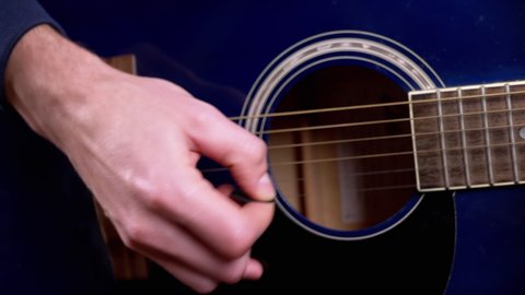 Male hands of a guitarist playing classical guitar at home. Musician-guitarist skillfully hits strings acoustic guitar with help of a mediator. Music concept. 4K. Close-up.