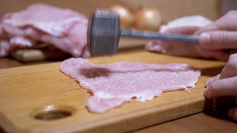 Hand of Cook Beats off a Delicious Juicy Piece of Pork Meat with Kitchen Hammer. Cooking Pork Chops. Fresh pieces of steak. Delicious healthy homemade food. Cook at home. Slow-motion. Close-up. 4K.