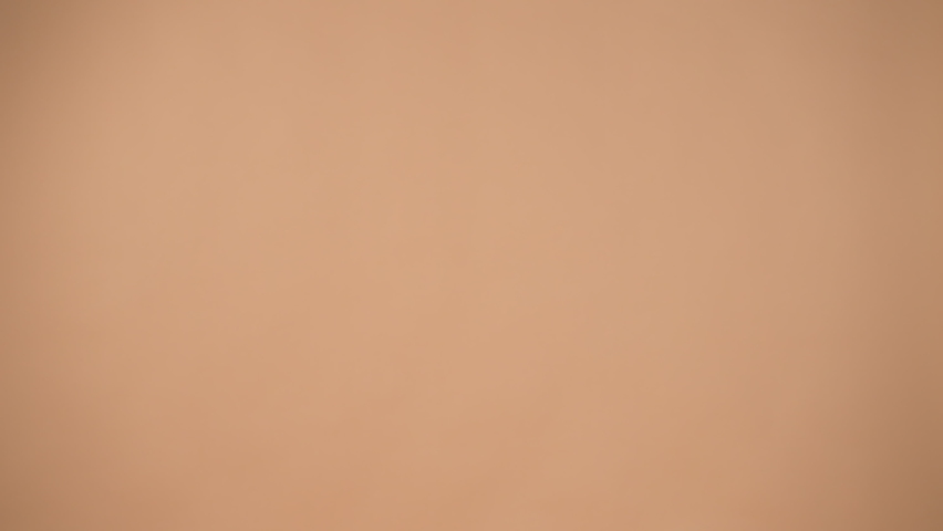 A cute girl in a blue dress and curly hair holds pink and white balloons and smiles cheerfully isolated on a peach gentle background.Valentine