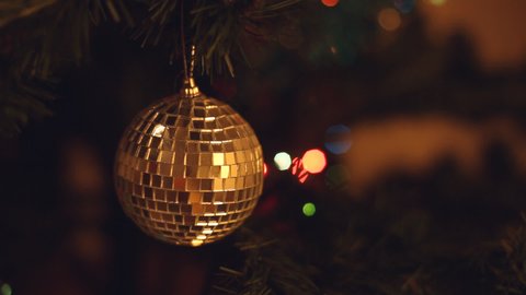Shuning disco party ball Christmas tree decoration in front of shimmery garland lights. Warm hipster colors and bokeh. An HD video footage for New Year Holiday clips