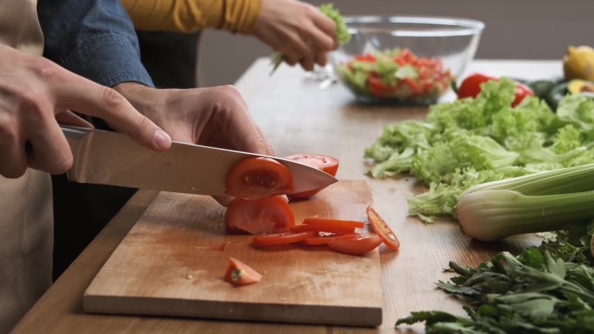 Cooking salad at home: man hands slicing a tomato for a salad. Side view. Healthy dinner meal concept 4k