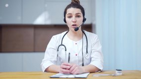 Woman medic worker video calling consulting patient online. Webcam view. Female doctor wears headset speaking looking at camera web cam providing remote medical assistance in virtual chat Telemedicine