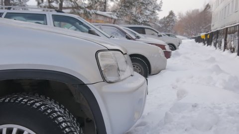 winter landscape. Cars stand in a parking lot near a metal fence in the snow in winter. Cars near the building in the winter parking. Snow and frost