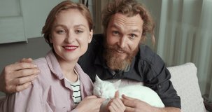 Webcam view young couple bearded Caucasian long-haired man husband and short-haired blonde woman with red lipstick filming video for blog make online call conference chat holding lovely pet cat kitty
