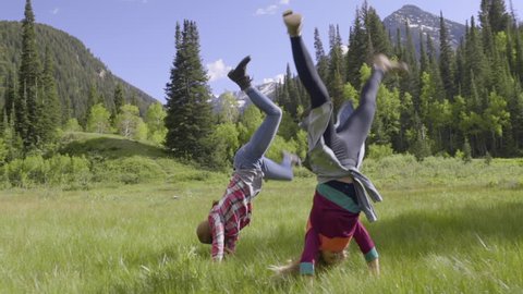 Carefree Teen Girls Practice Cartwheels In Mountain Meadow (Slow Motion)