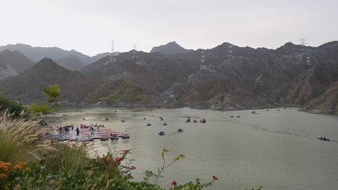 BEAUTIFUL 4K TIMELAPSE AERIAL VIDEO OF MOVEMENT OF BOATS, KAYAKS IN THE RAFIS WATER DAM  AT SUNSET TIME IN THE MOUNTAINS ENCLAVE REGION OF KHOR FAKKAN, UNITED ARAB EMIRATES