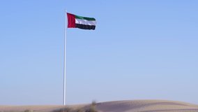 4K video of the flag of United Arab Emirates waving in the wind positioned on the sandy deserts of Dubai UAE.