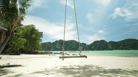 Strong wind swinging wooden swing hang on a tree with view seascape Phi Phi island, Krabi, Southern of Thailand in summer season, nature landscape holiday, summer beach
