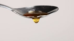 liquid honey drips down from a silver spoon. Honey drops 