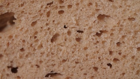 Close up of a fresh organic bread loaf being squeezed and the pores compressed. Mouthwatering homemade bread with crispy crust and soft dough. Tasty and healthy food texture. Macro, 4K.