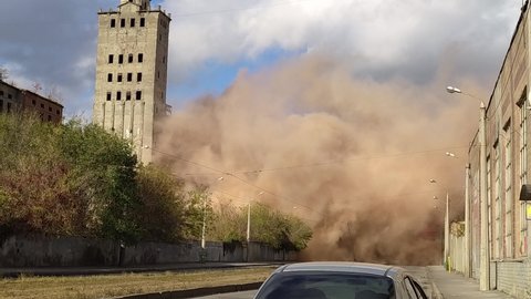 A controlled explosion of an old building. Demolition of a building on the territory of the plant. Highly dusty air after explosion.